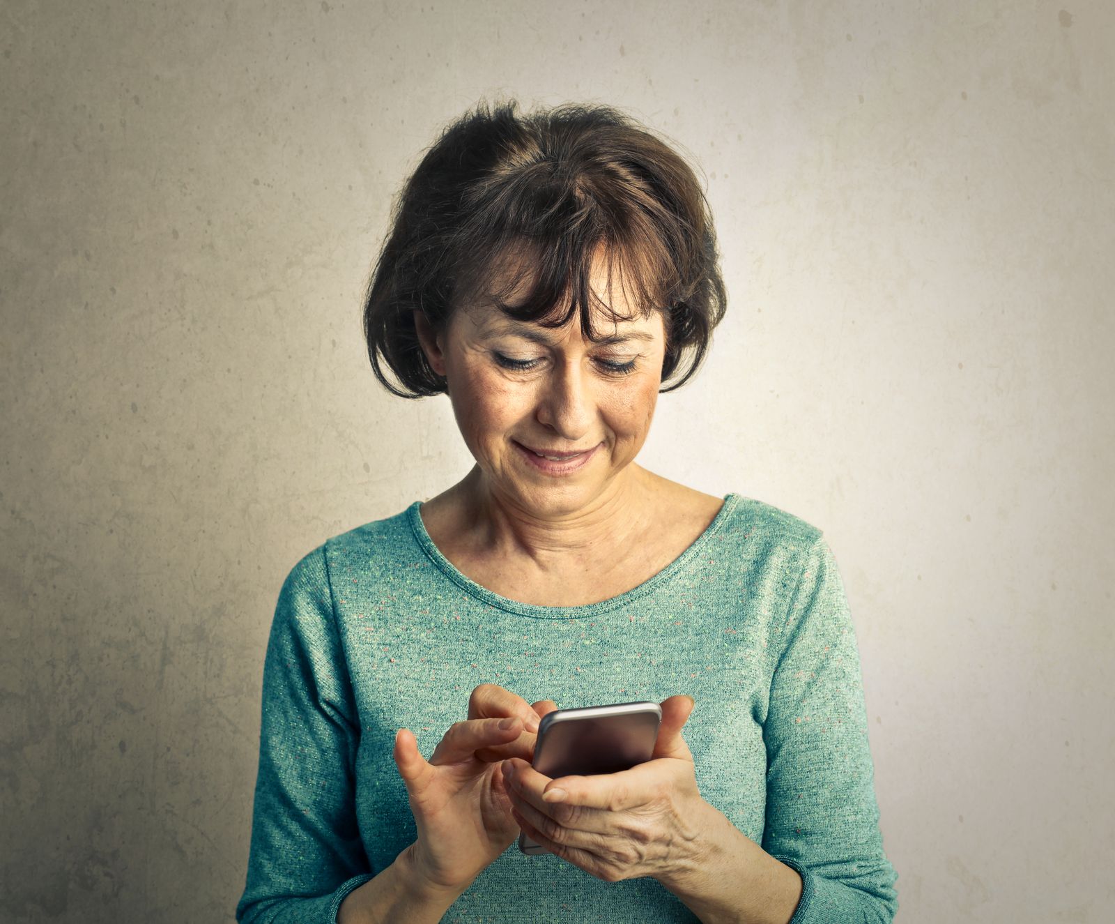 Mujer mayor sonriendo mientras usa su celular