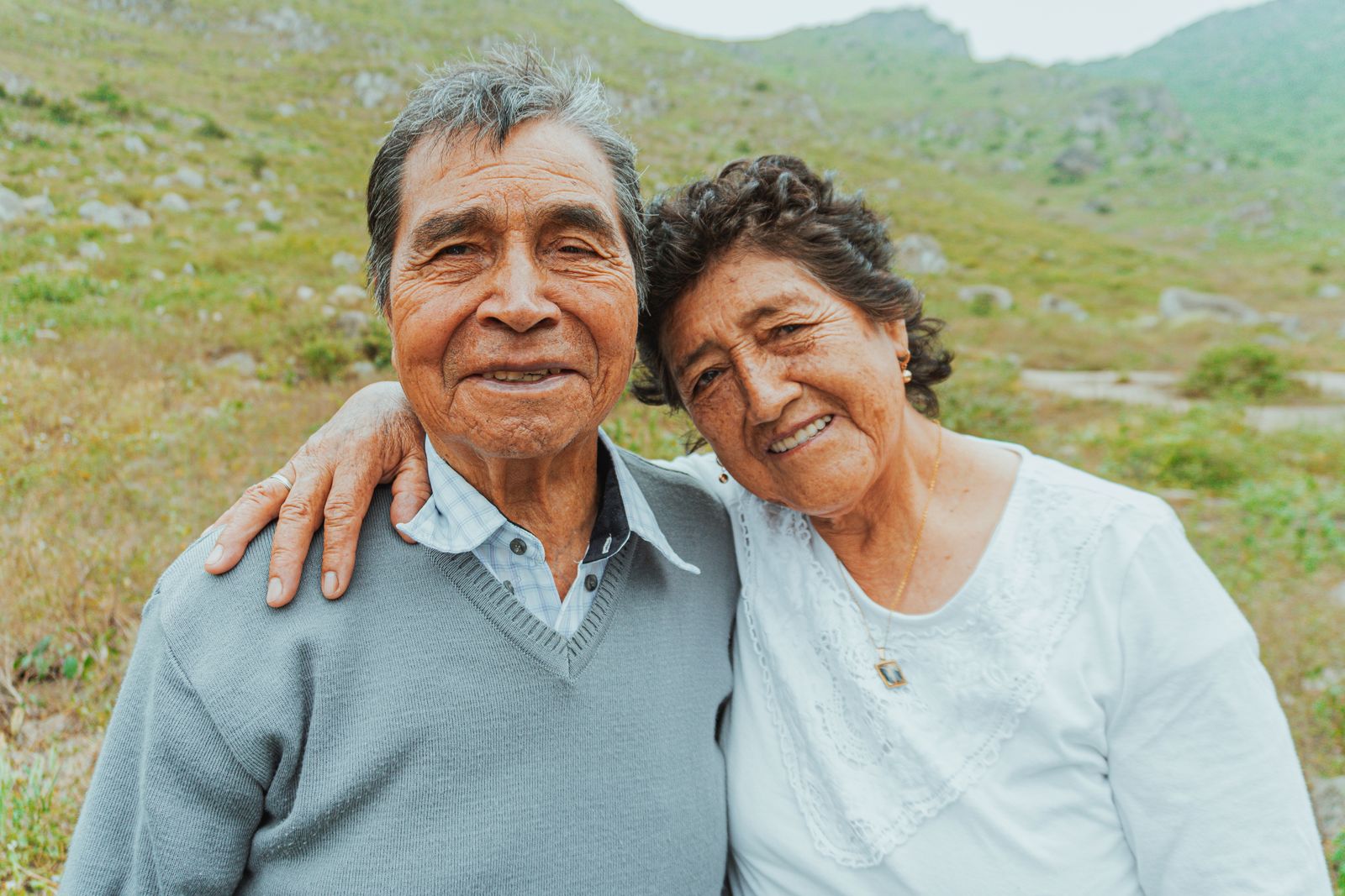 Pareja de adultos mayores abrazados sonriendo al aire libre